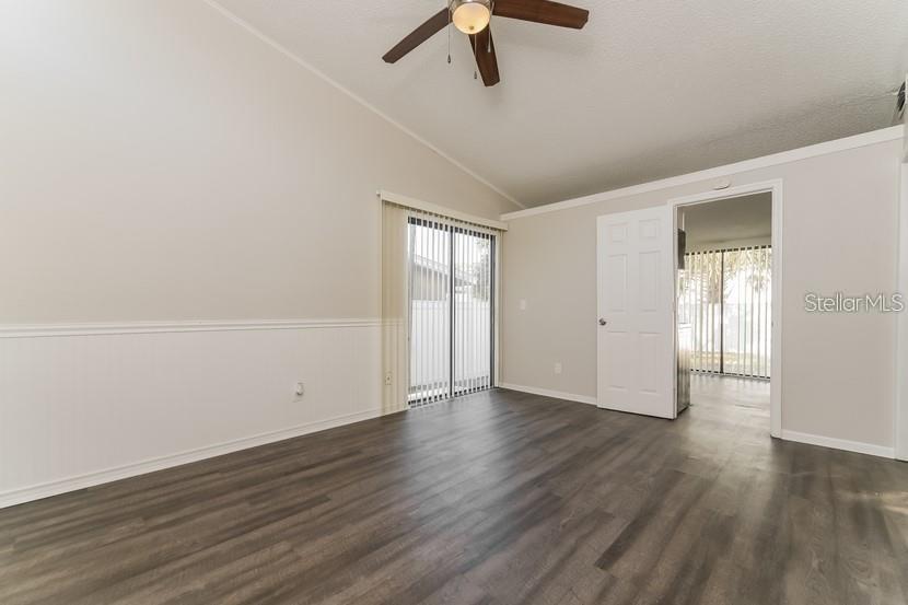 An empty room features wood-look flooring, a ceiling fan, a sliding glass door, and wainscoting — 559 MARTIN PLACE BOULEVARD, APOPKA, FL