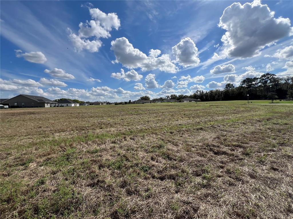 A wide, grassy vacant lot under a bright blue sky with scattered clouds — 000 NW 79TH LOOP Lot 14, OCALA, FL