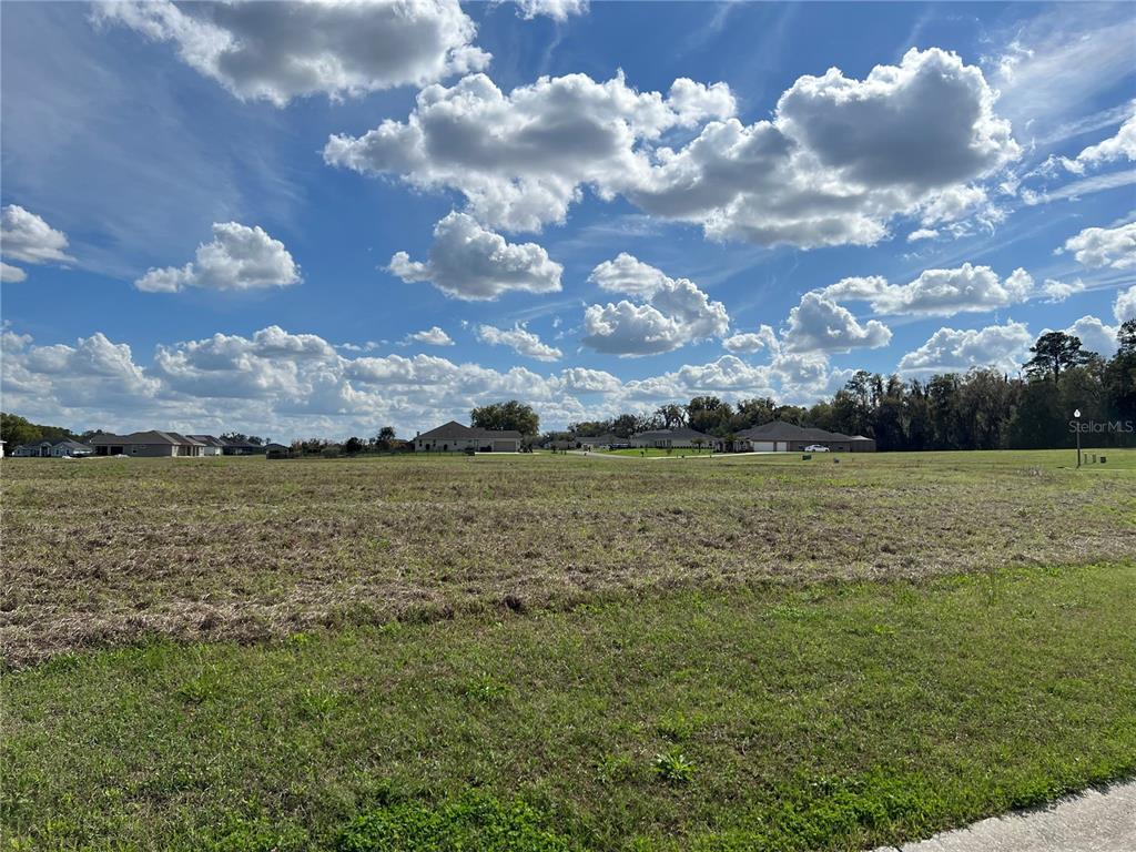 A wide, grassy vacant lot under a bright blue sky with scattered clouds — 000 NW 79TH LOOP Lot 14, OCALA, FL