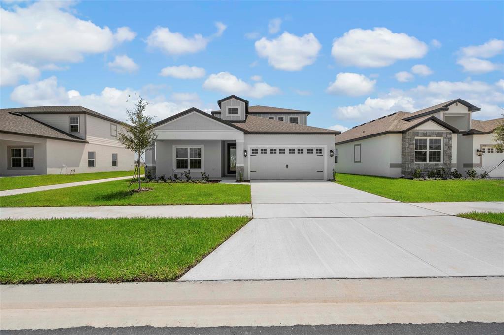 A single-story suburban house with a gray exterior, a two-car garage, and a front lawn — 3371 CHINOTTO DRIVE, LAKE ALFRED, FL
