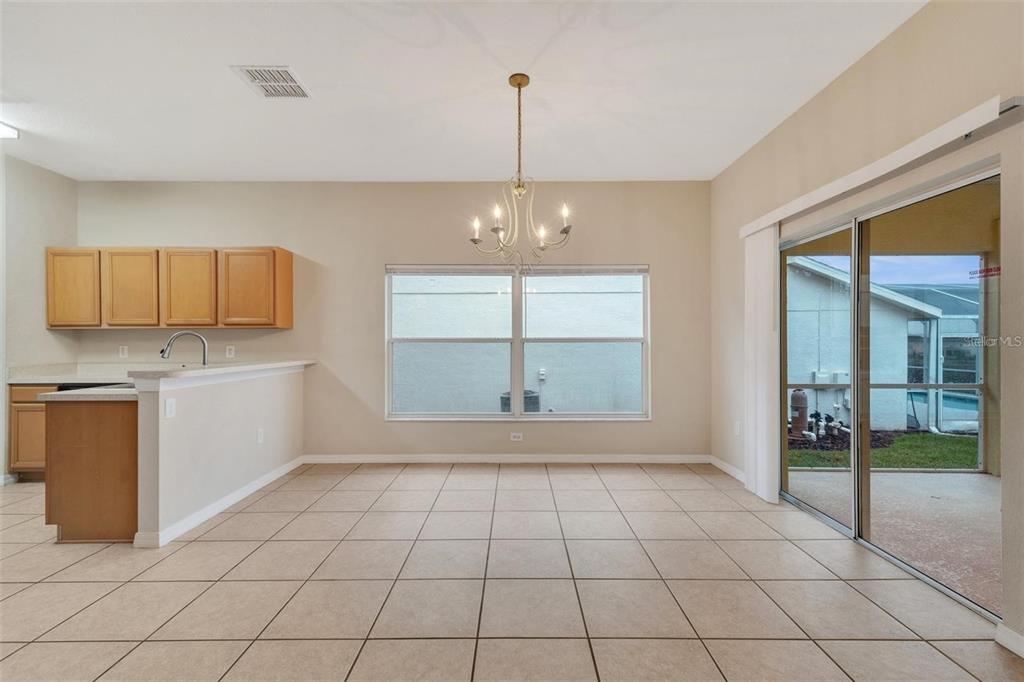 A dining area with tile floors, a chandelier, and sliding glass doors leading to a patio — 318 WINDSOR PLACE, DAVENPORT, FL