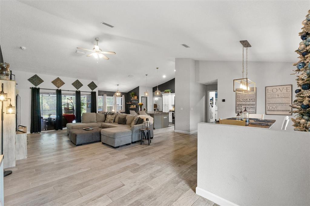 An open-concept living and dining area features light wood-look tile floors and a gray sectional — 4631 N RUSHMORE LOOP, BEVERLY HILLS, FL