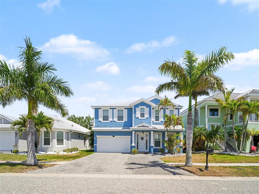 A two-story blue house with a white garage and palm trees in the front yard — 6417 KEY ISLAND AVE, APOLLO BEACH, FL