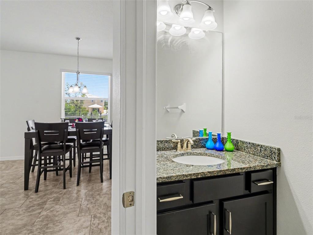 A bathroom vanity with granite countertops sits beside a view into a dining room — 6417 KEY ISLAND AVE, APOLLO BEACH, FL