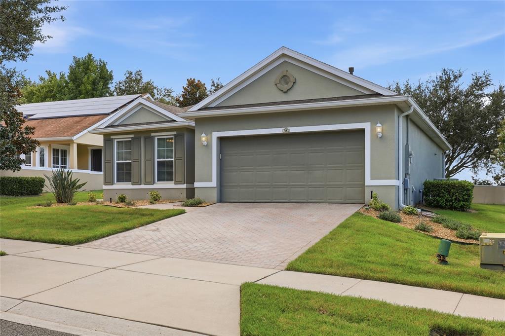A single-story house with a two-car garage, a paved driveway, and a light green exterior — 381 SILVER MAPLE ROAD, GROVELAND, FL