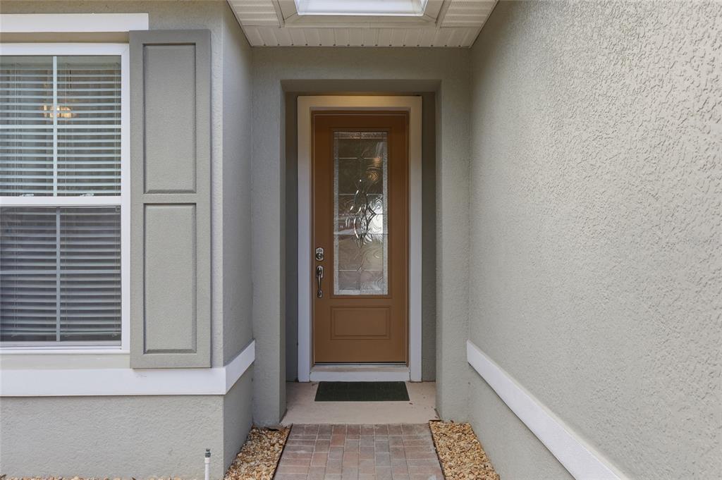 A brown front door with a glass insert sits under a covered entryway — 381 SILVER MAPLE ROAD, GROVELAND, FL