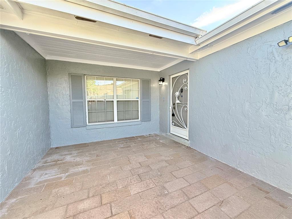 A covered patio features light gray stucco walls, a tiled floor, and a white storm door — 1739 LAKE MARION DRIVE, APOPKA, FL