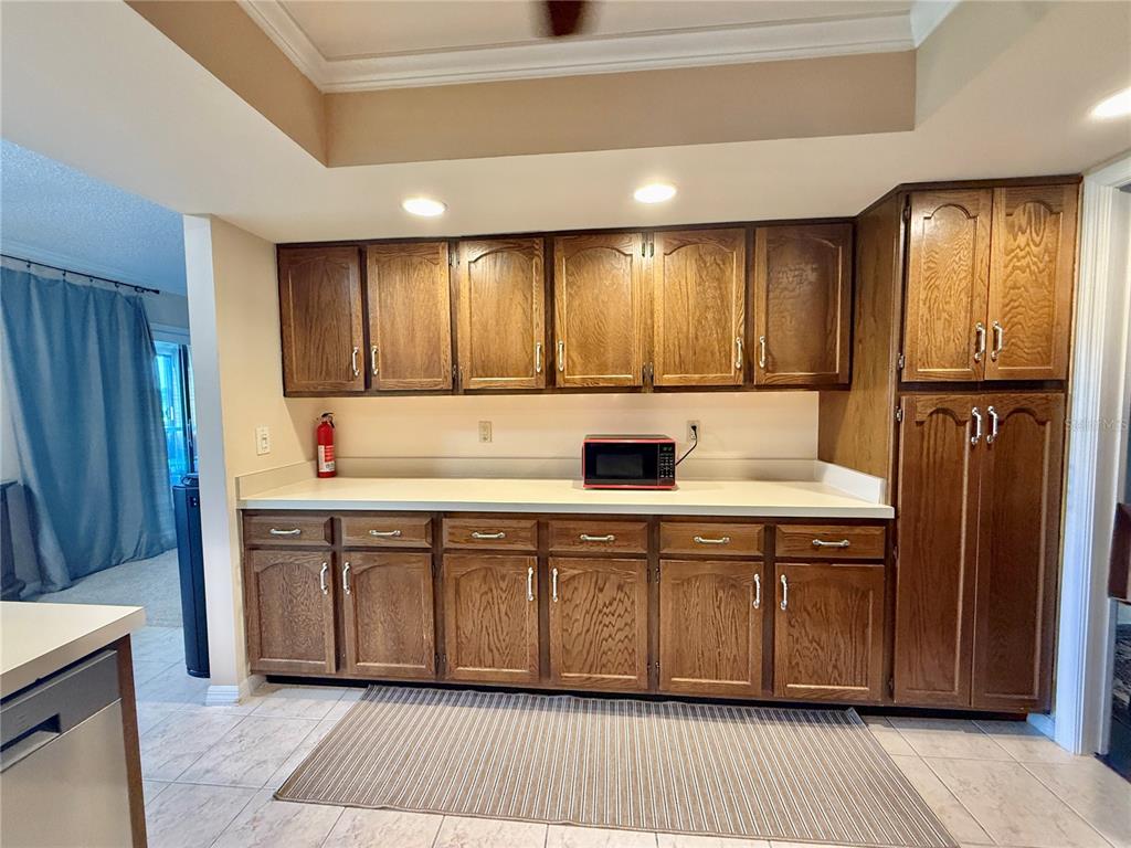 A kitchen features wood cabinets, a light countertop, a red microwave, and tiled flooring — 1739 LAKE MARION DRIVE, APOPKA, FL