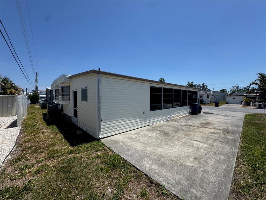 The exterior of a light-colored mobile home features a concrete driveway and a screened porch — 1111 49TH AVE TERRACE W, BRADENTON, FL