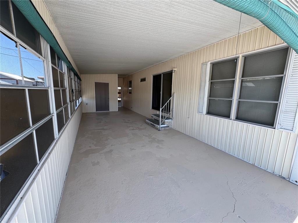 A covered outdoor patio features a concrete floor, beige siding, and a sliding glass door — 1111 49TH AVE TERRACE W, BRADENTON, FL