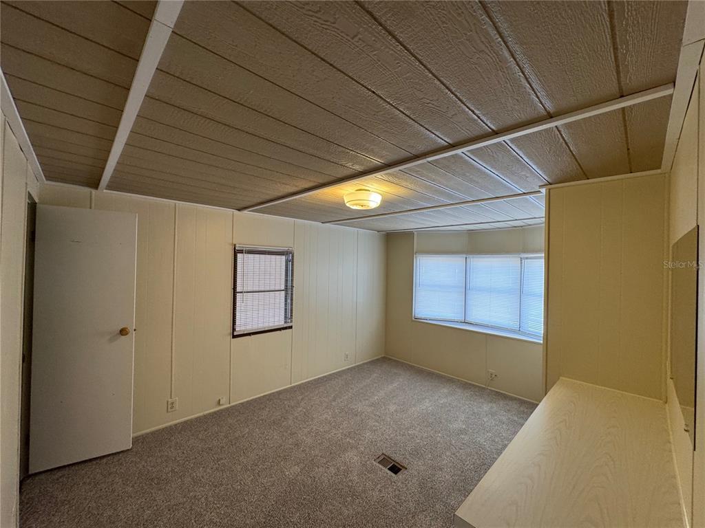 A bedroom features wood-paneled walls, a drop ceiling, carpeted flooring, and a built-in desk — 1111 49TH AVE TERRACE W, BRADENTON, FL