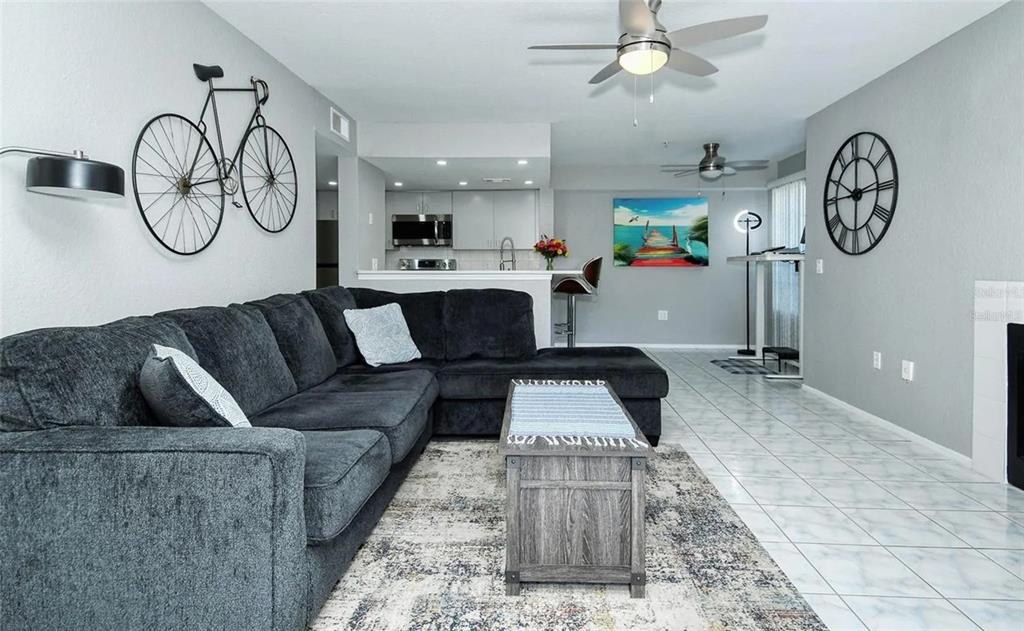 A living room with a dark sectional sofa, area rug, and open kitchen in the background — 850 S TAMIAMI TRAIL UNIT 801, SARASOTA, FL