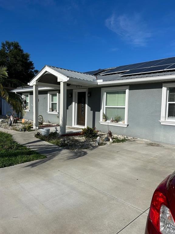 The exterior view shows a covered concrete porch with white columns and a dark door — 9724 TOM FOLSOM ROAD, THONOTOSASSA, FL