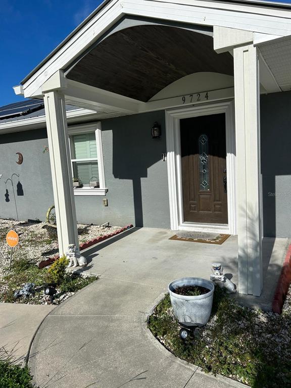 A gray house exterior features a covered entryway with a dark wood ceiling and columns — 9724 TOM FOLSOM ROAD, THONOTOSASSA, FL
