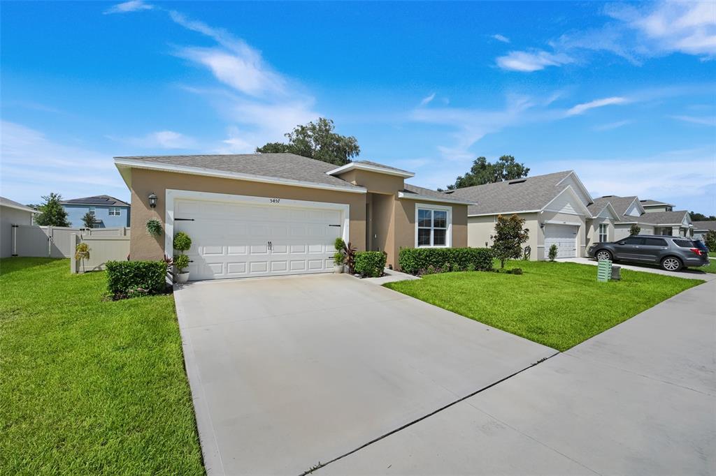 A tan single-story house with a two-car garage and a concrete driveway — 5457 HAYLOFT DRIVE, APOPKA, FL