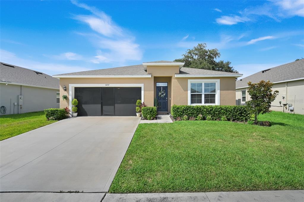 A single-story house with a tan stucco exterior, a two-car garage, and a front lawn — 5457 HAYLOFT DRIVE, APOPKA, FL