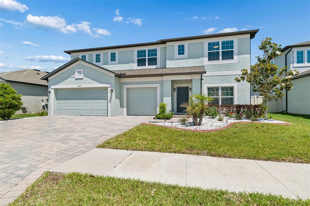 A two-story house with a light blue stucco exterior, a paved driveway, and two garages — 17647 CORTES CREEK BOULEVARD, SPRING HILL, FL