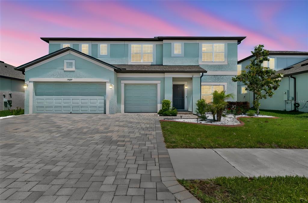 A two-story house with a light blue exterior, three-car garage, and a paved driveway — 17647 CORTES CREEK BOULEVARD, SPRING HILL, FL