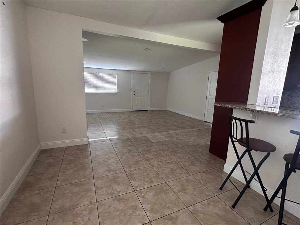 A tiled room features a breakfast bar with stools and an open doorway to another area — 503 BROXBURN AVENUE, TEMPLE TERRACE, FL
