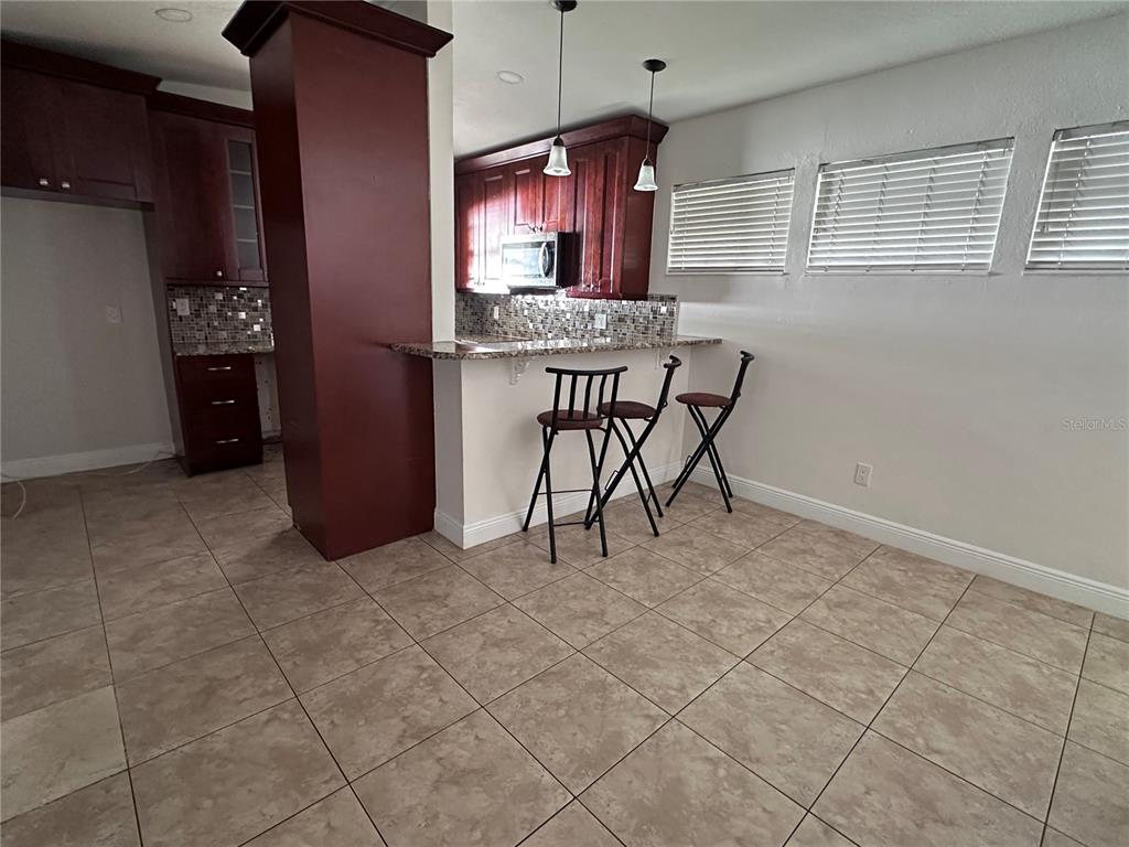 A kitchen features dark wood cabinets, a granite breakfast bar, and tile flooring — 503 BROXBURN AVENUE, TEMPLE TERRACE, FL