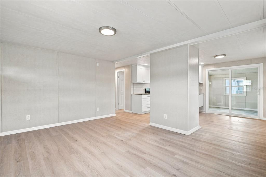An interior view of a living area with light wood flooring and white paneled walls — 10912 JUSTICE DRIVE, PORT RICHEY, FL