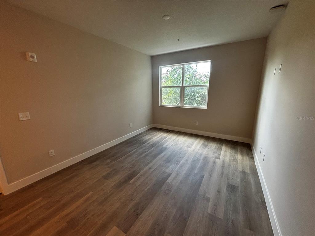 A kitchen features wood-grain cabinets, granite countertops, stainless steel appliances, and wood-look flooring — 4424 S TEXAS AVENUE UNIT 1-205, ORLANDO, FL