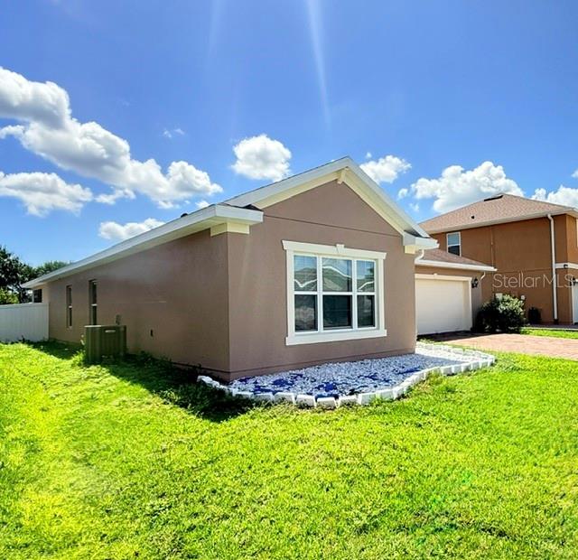 A tan, single-story house exterior features a white-trimmed window and a white rock garden border — 2365 BARTON BAY COURT, KISSIMMEE, FL