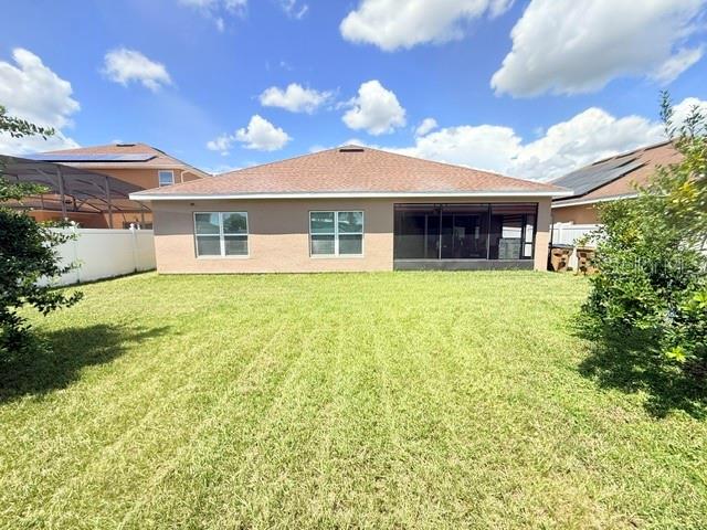 The rear exterior of a single-story house features a lawn, a screened patio, and windows — 2365 BARTON BAY COURT, KISSIMMEE, FL