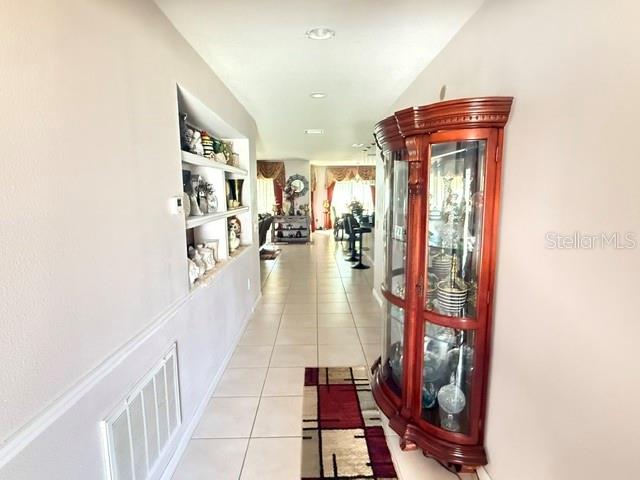 A hallway features a built-in wall niche, a wooden curio cabinet, and tiled flooring — 2365 BARTON BAY COURT, KISSIMMEE, FL