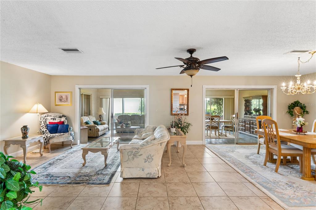 A living and dining area with tile flooring, a ceiling fan, and sliding glass doors — 1520 PALMER COURT, PALM HARBOR, FL