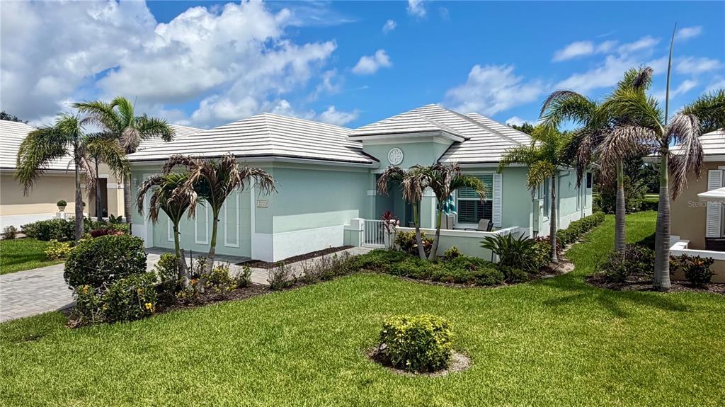 A light green single-story house with a white tile roof and palm trees in front — 1330 SAINT CATHERINES CIRCLE, VERO BEACH, FL