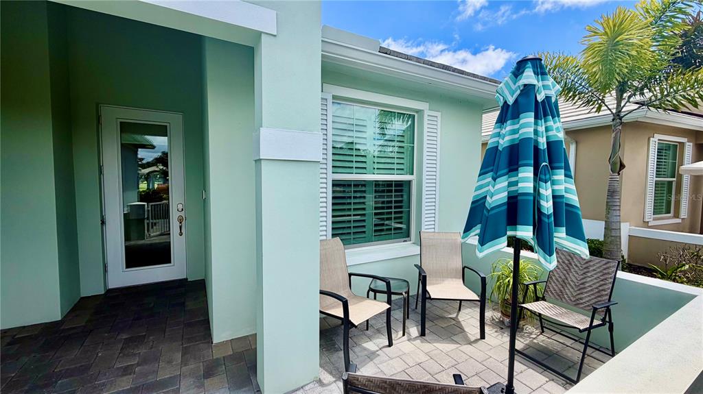 A paved patio features a small table, three chairs, and a blue striped umbrella — 1330 SAINT CATHERINES CIRCLE, VERO BEACH, FL