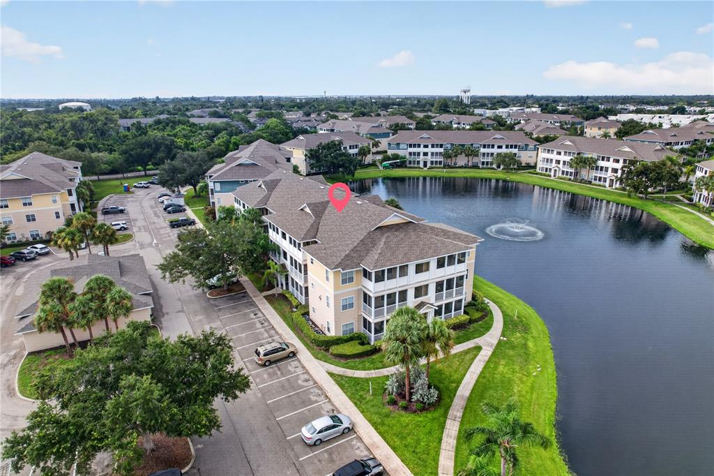 An aerial view shows a multi-story apartment building situated next to a pond — 4802 51ST STREET W UNIT 1912, BRADENTON, FL