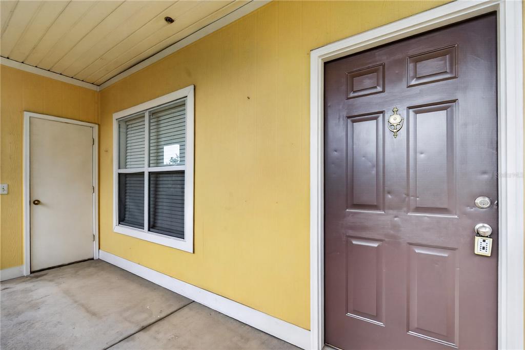 A yellow exterior wall features a brown front door and a white-framed window — 4802 51ST STREET W UNIT 1912, BRADENTON, FL