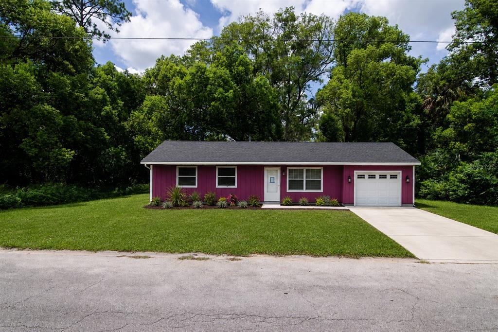 A magenta single-story house with a white garage door sits behind a green lawn — 504 N 18TH STREET, PALATKA, FL