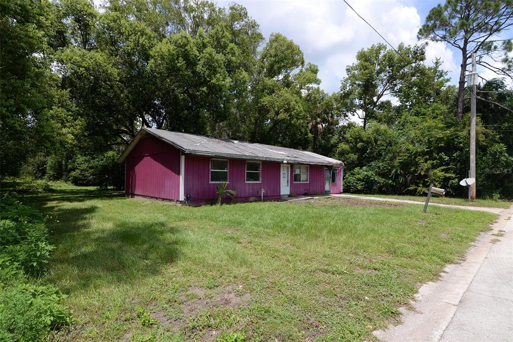 A magenta-colored, single-story house with a metal roof sits on a grassy lot — 504 N 18TH STREET, PALATKA, FL