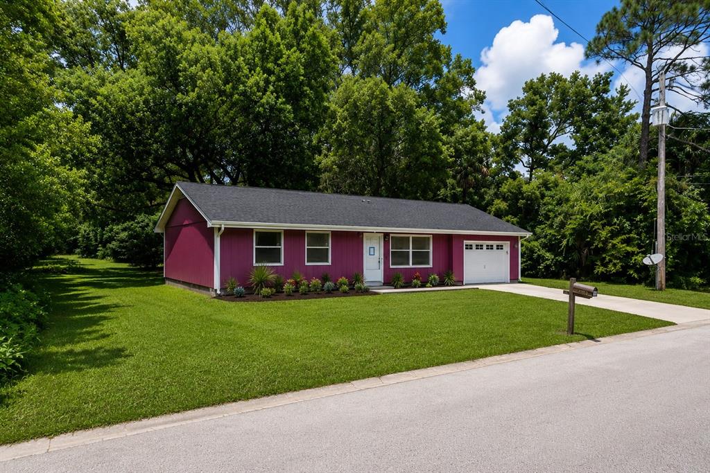A single-story house with magenta siding, a dark shingled roof, and an attached garage — 504 N 18TH STREET, PALATKA, FL