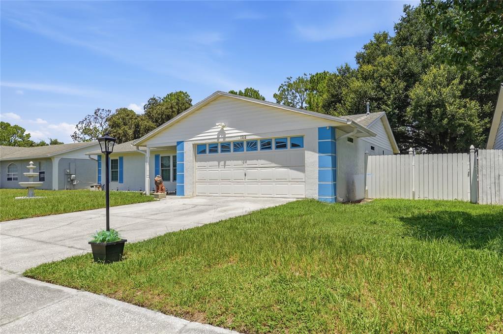 A single-story house with a white garage, blue accents, and a concrete driveway — 133 REBECCA DRIVE NE, WINTER HAVEN, FL
