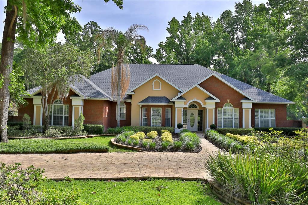 A single-story brick and stucco house features a paved driveway and a landscaped front yard — 7122 SE 12TH CIRCLE, OCALA, FL