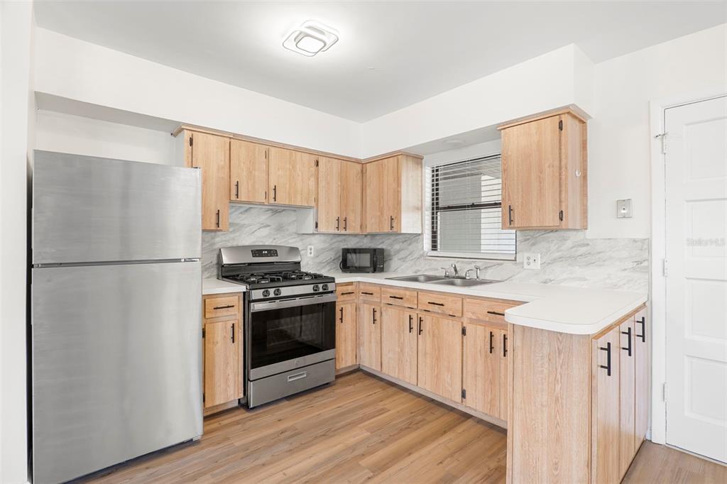 A kitchen features light wood cabinets, stainless steel appliances, and a marble-patterned backsplash — 2189 S SMATHERS CIRCLE, MELBOURNE, FL