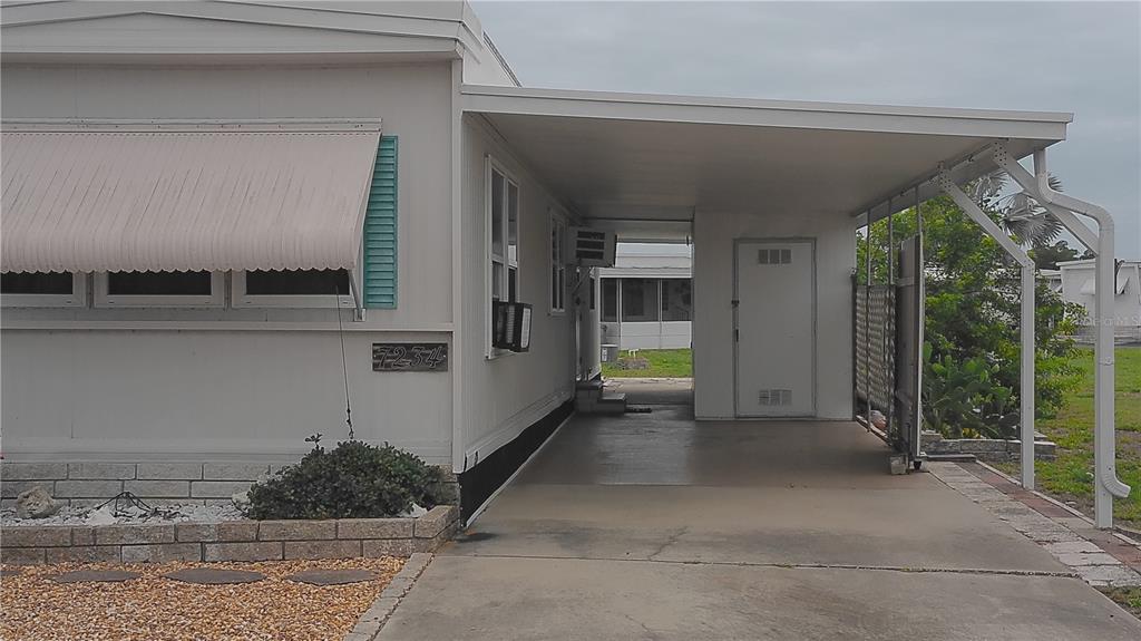 A mobile home exterior features a concrete driveway, a covered carport, and a white door — 7234 MOUNT FAIRFIELD ROAD NE UNIT 529, ST PETERSBURG, FL