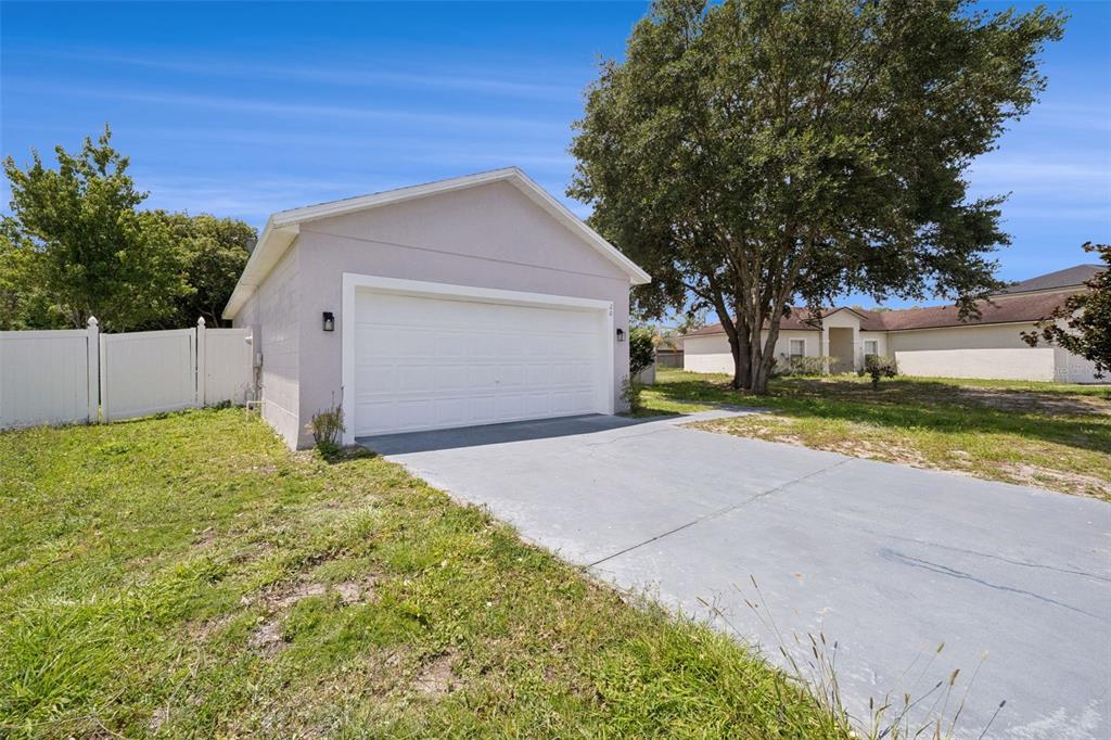 A detached garage with a white door and concrete driveway sits on a grassy lot — 20 COVENTRY COURT, KISSIMMEE, FL