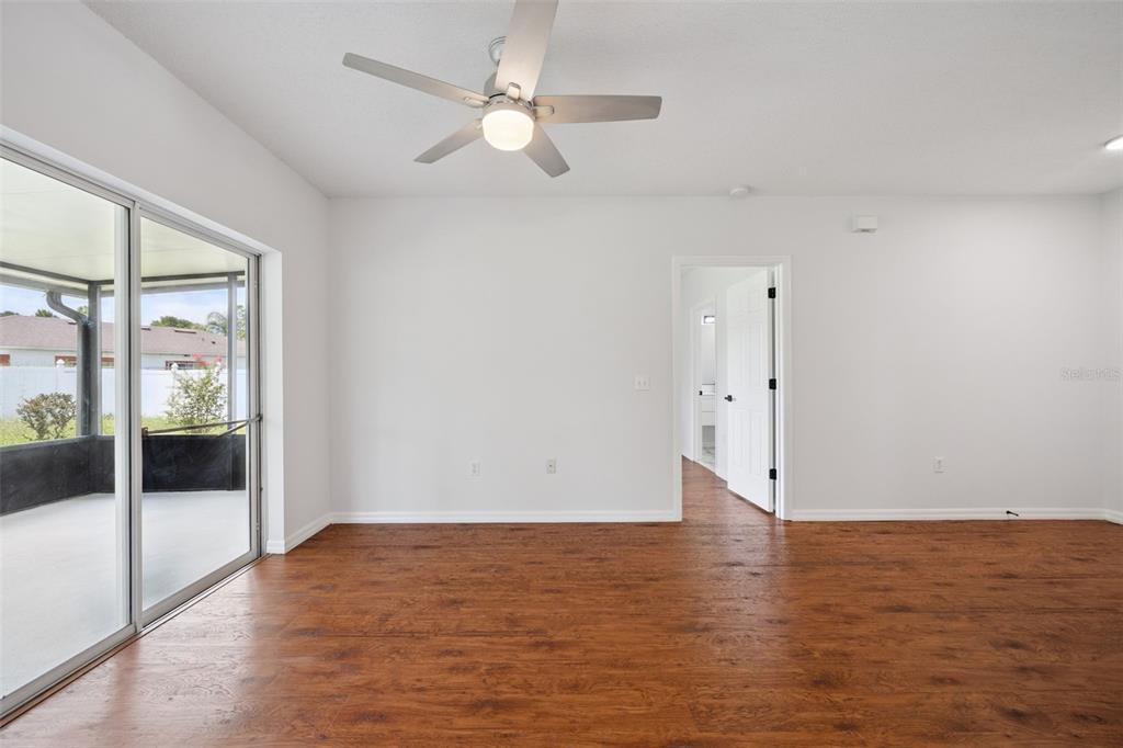 An empty room with wood-look flooring, a ceiling fan, and sliding glass doors to a patio — 20 COVENTRY COURT, KISSIMMEE, FL