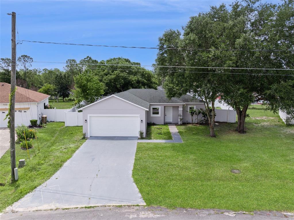 A single-story house with a gray exterior, a two-car garage, and a large front lawn — 20 COVENTRY COURT, KISSIMMEE, FL