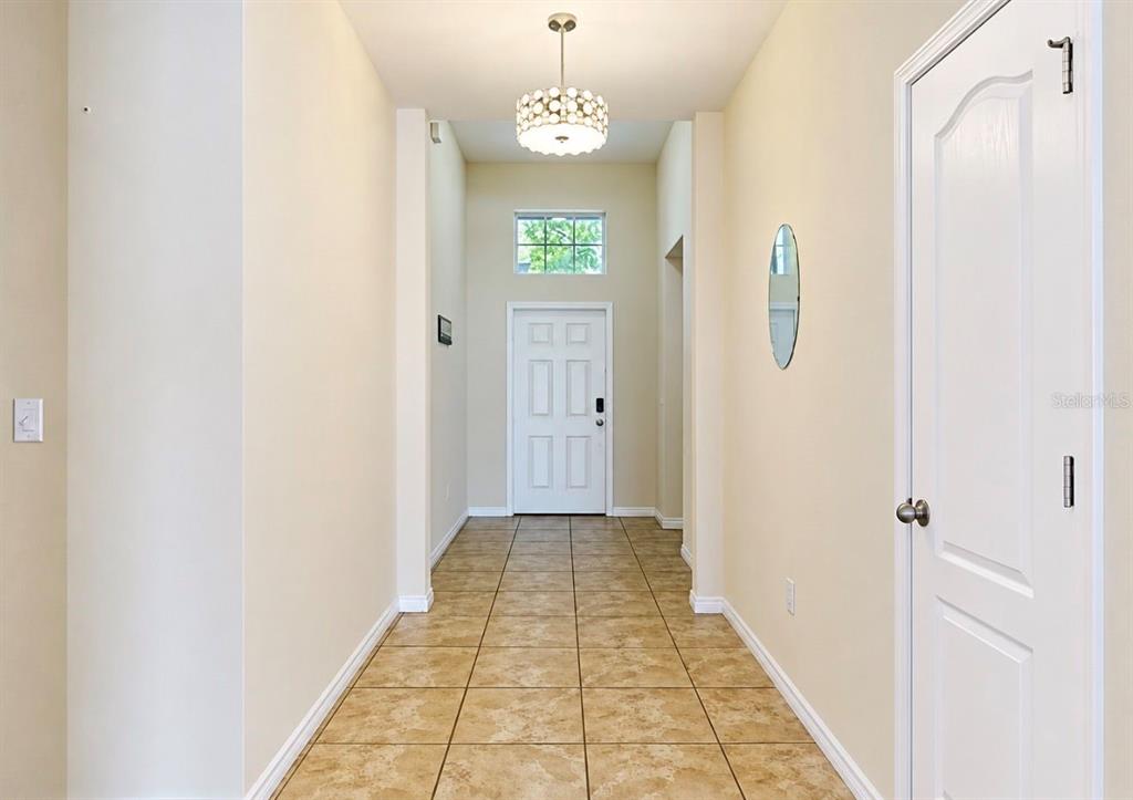 A tiled entryway features a white front door, a transom window, and a decorative light fixture — 619 WABASH BREEZE CIRCLE, RUSKIN, FL