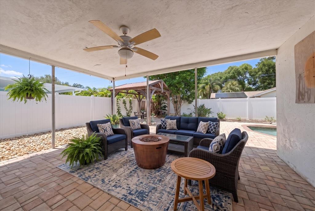 A covered patio features wicker furniture, a fire pit, and a pool in the backyard — 10928 118TH STREET, SEMINOLE, FL