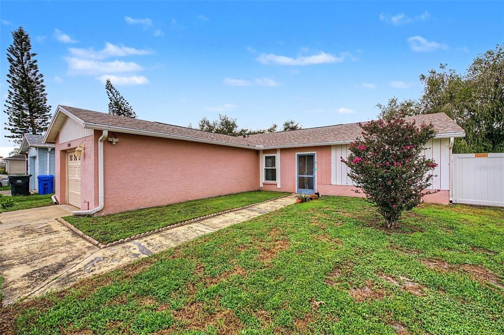 A single-story pink house with a tan roof, a concrete driveway, and a front lawn — 1004 COOLWOOD PLACE, BRANDON, FL