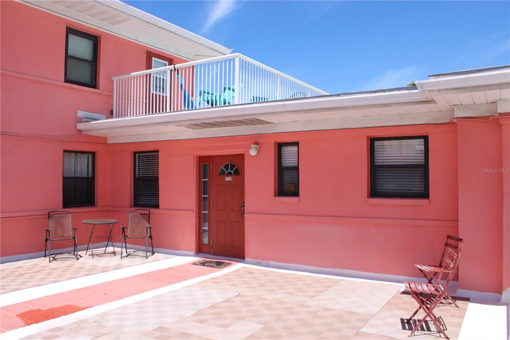 A pink exterior building features a patio, a second-story balcony, and a red front door — 6800 SUNSET WAY UNIT 1708, ST PETE BEACH, FL