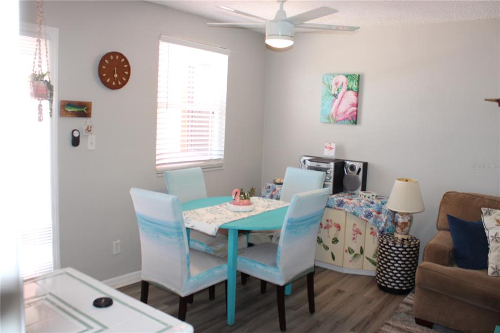 A dining area features a turquoise table, matching chairs, a ceiling fan, and flamingo decor — 6800 SUNSET WAY UNIT 1708, ST PETE BEACH, FL