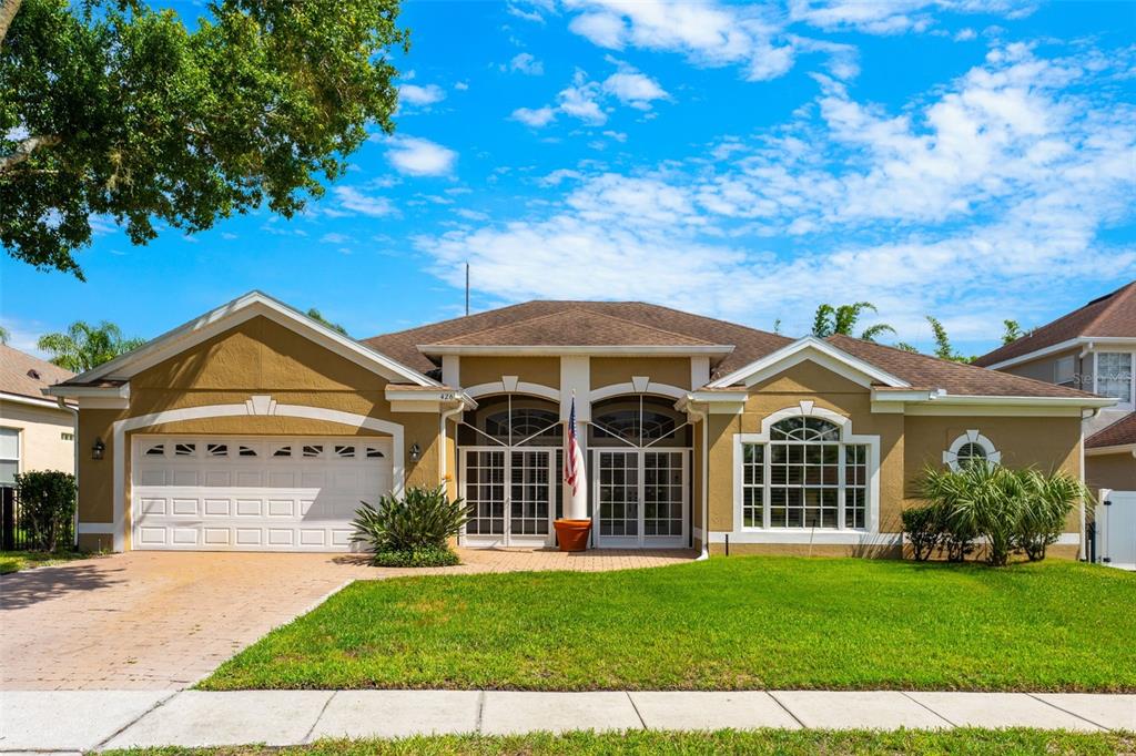 A single-story house with a tan stucco exterior, a two-car garage, and a paved driveway — 426 PALM CREST LANE, LAKE MARY, FL
